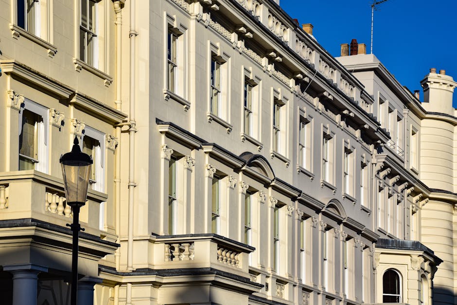 A close-up view of the exterior facade of a historic Victorian building in Pimlico, London, showcasing cream-colored stone walls with ornate architectural details. The building features multiple tall,