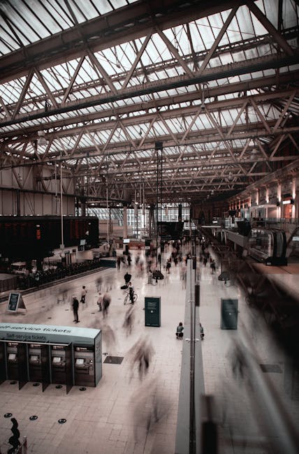 View of a modern, tiled commercial space at Victoria station, seen through a rounded window. The space features wooden wall panels, a grey floor, and a ceiling with suspended lighting fixtures. There 